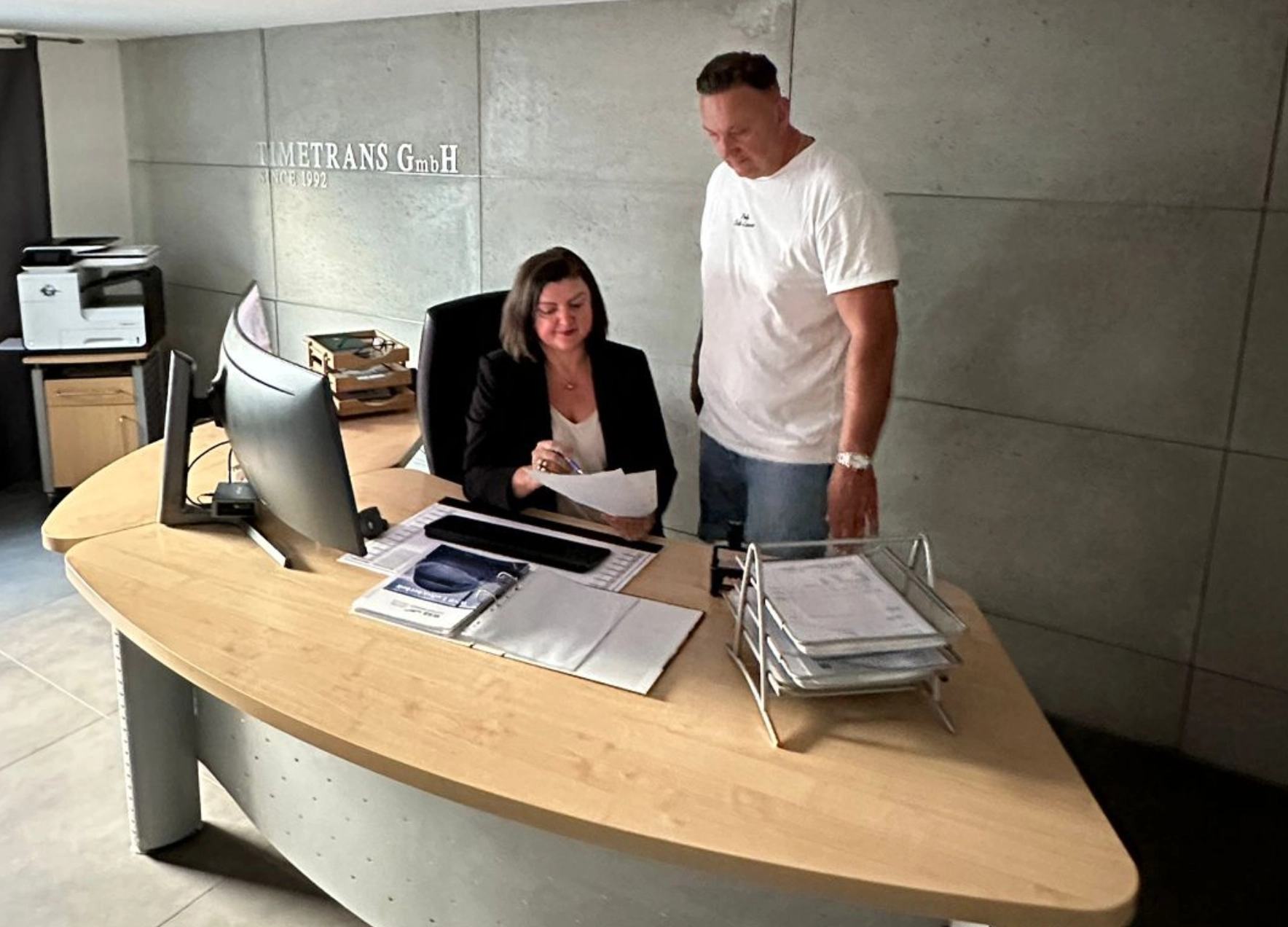 Ein Mann und eine Frau in einem modernen Büro vor einem Schreibtisch.